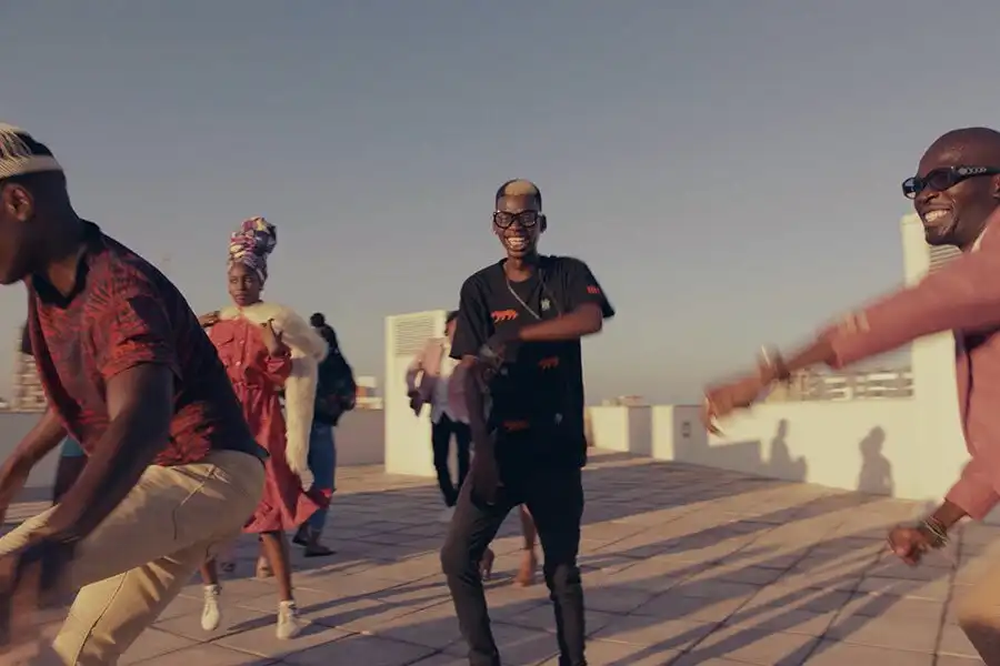 People joyfully dancing on a rooftop under a clear sky, expressing happiness and energy.