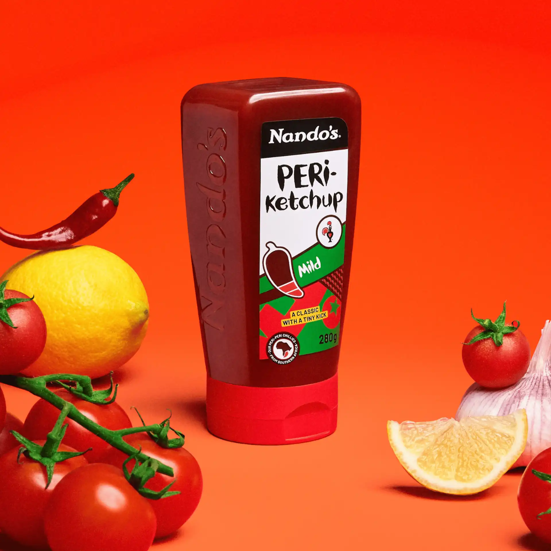 Nando's PERi-Ketchup bottle surrounded by tomatoes, garlic, lemon, and chili on a vibrant orange background.